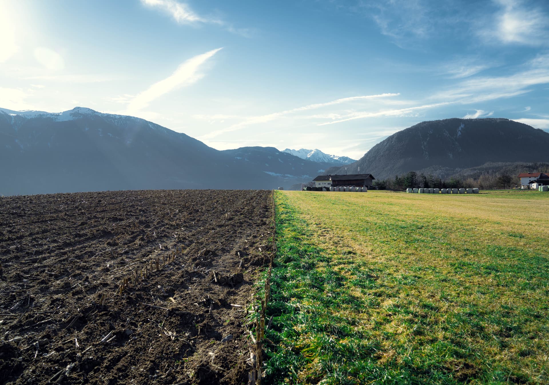 Campo labrado junto a la hierba y las montañas